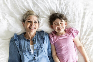 Lächelnde Mutter und Tochter auf dem Bett liegend - WPEF07596