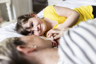 Daughter resting with mother on bed at home - WPEF07609