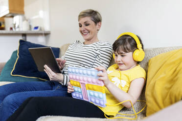 Lächelnde Mutter und Tochter mit Tablet-PCs auf dem Sofa sitzend - WPEF07611