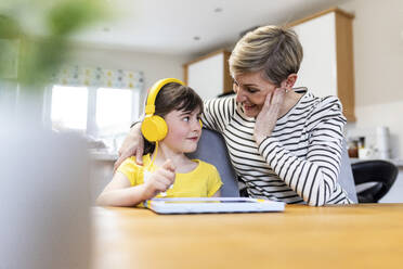 Lächelnde Mutter im Gespräch mit ihrer Tochter, die einen Tablet-PC zu Hause hält - WPEF07613