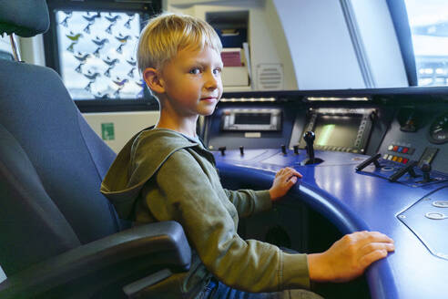 Smiling boy sitting in cockpit of train engine - NJAF00539