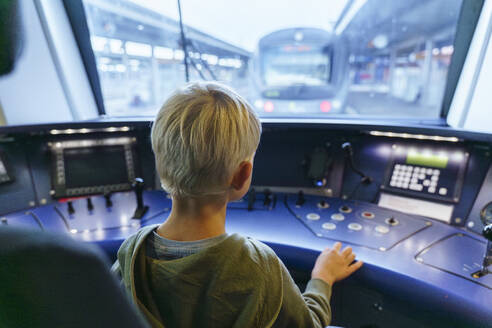 Junge sitzt im Cockpit einer Zugmaschine - NJAF00540