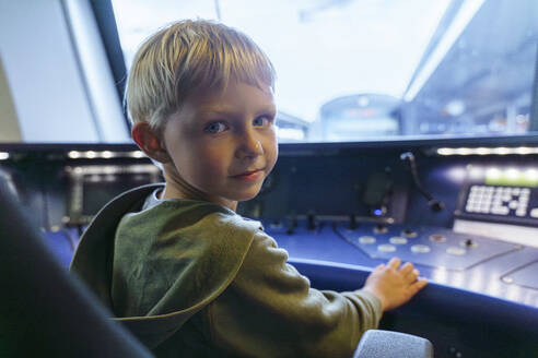 Lächelnder blonder Junge sitzt im Cockpit einer Zuglokomotive - NJAF00541