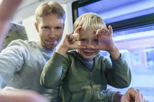 Smiling man taking selfie with son in train - NJAF00550