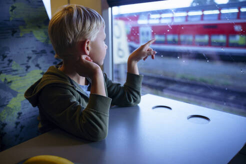 Junge berührt Glasfenster im Zug sitzend - NJAF00552