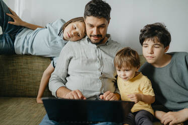 Kinder mit Vater, die zu Hause einen Laptop benutzen - ANAF01989