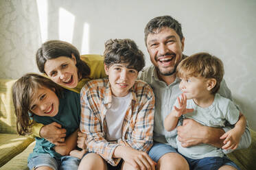 Happy family together sitting on sofa at home - ANAF01991