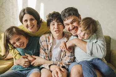 Glückliche Familie, die zusammen auf dem Sofa sitzt und Spaß zu Hause hat - ANAF01992