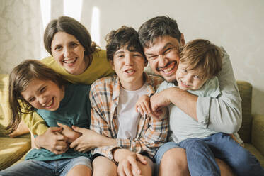 Happy family together sitting on sofa and having fun at home - ANAF01992