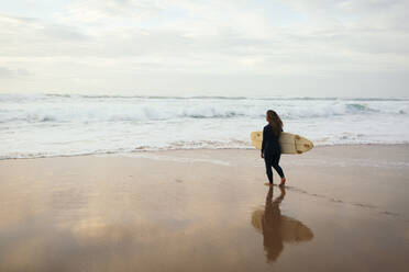 Frau mit Surfbrett geht am Strand Richtung Meer - DCRF01760