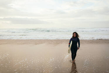 Lächelnde Frau mit Surfbrett am Strand - DCRF01762