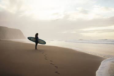 Footprints leading surfer with surfboard standing bear sea - DCRF01768