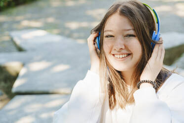 Glücklicher Teenager, der Musik über kabellose Kopfhörer hört - IHF01589