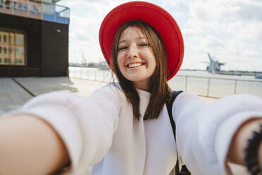 Smiling teenage girl taking selfie at harbor - IHF01596