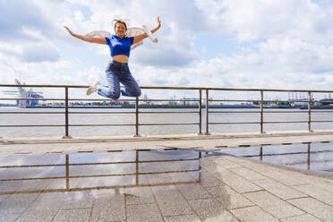 Carefree teenager jumping in front of Elbe river - IHF01599