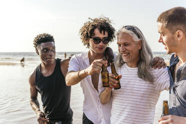 Fröhliche multiethnische Freunde beim Bier am Strand im Urlaub - PBTF00145