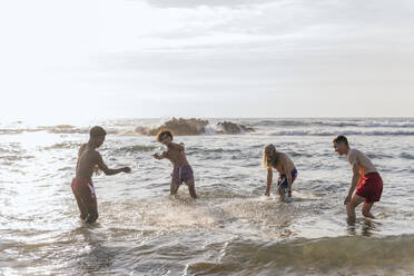 Fröhliche multiethnische Freunde spielen im Meer im Urlaub - PBTF00155