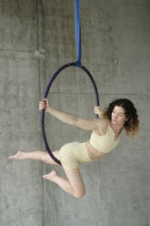 Frau übt Gymnastik am Luftreifen vor einer Betonwand - YHF00077