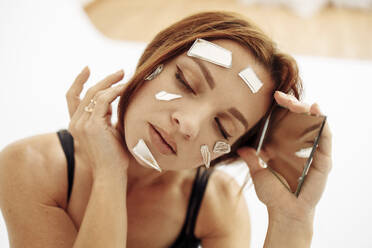 Zerbrochene Spiegelstücke auf dem Gesicht einer Frau - ASTF05069
