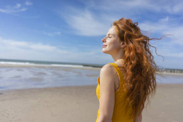 Woman enjoying wind at beach on vacation - KNSF09711