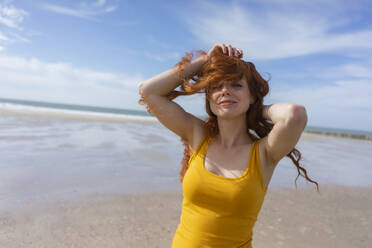 Frau spielt mit zerzaustem Haar am Strand im Urlaub - KNSF09712