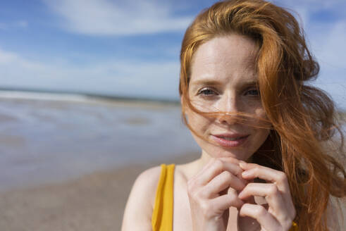 Frau mit Wind im Haar am Strand an einem sonnigen Tag - KNSF09713