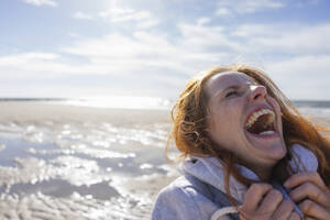 Frau lachend am Strand im Urlaub - KNSF09717