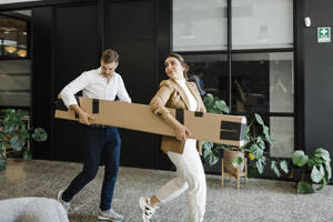 Geschäftskollegen helfen sich gegenseitig beim Tragen von Paketen im Büro - DCRF01783