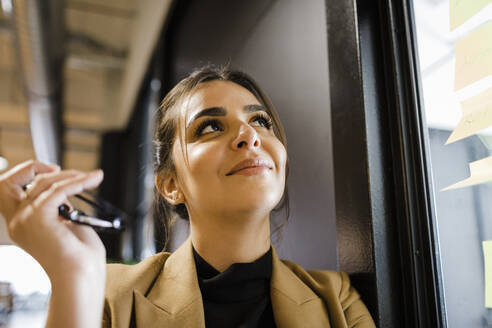 Smiling businesswoman day dreaming at office - DCRF01796