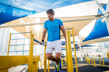 Junger sportlicher Mann beim Training im Freien - Junger Erwachsener beim Fitnesstraining - DMDF03002