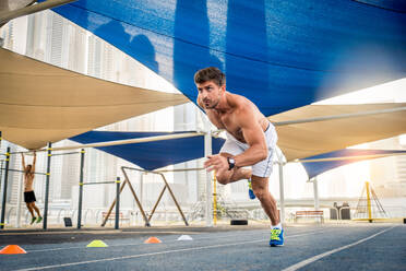 Young athletic man training outdoors - Young adult doing a fitness workout - DMDF03009