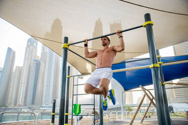 Junger sportlicher Mann beim Training im Freien - Junger Erwachsener beim Fitnesstraining - DMDF03023