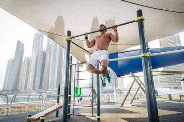 Junger sportlicher Mann beim Training im Freien - Junger Erwachsener beim Fitnesstraining - DMDF03024