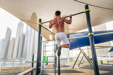 Junger sportlicher Mann beim Training im Freien - Junger Erwachsener beim Fitnesstraining - DMDF03025