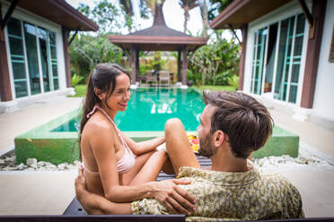 Couple of lovers in a beautiful villa with swimming pool in a tropical climate location - Happy people on a summer vacation, influencers enjoying a luxury resort - DMDF03059