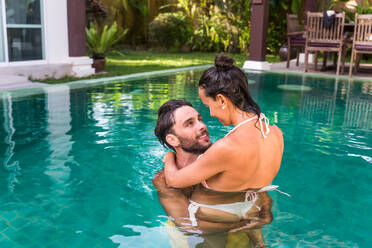 Couple of lovers in a beautiful villa with swimming pool in a tropical climate location - Happy people on a summer vacation, influencers enjoying a luxury resort - DMDF03073