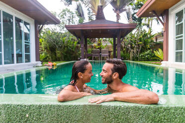 Couple of lovers in a beautiful villa with swimming pool in a tropical climate location - Happy people on a summer vacation, influencers enjoying a luxury resort - DMDF03089