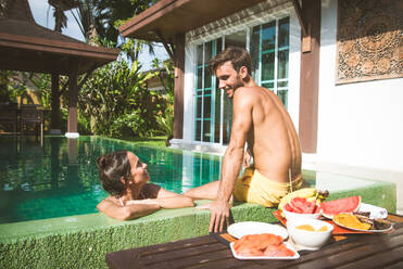 Couple of lovers in a beautiful villa with swimming pool in a tropical climate location - Happy people on a summer vacation, influencers enjoying a luxury resort - DMDF03097