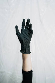 Hand wearing black plastic glove - SVCF00385