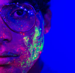Portrait of fashionable man with colored fluo painting on the face - Fashion model on colored background - DMDF03174