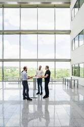 Group of businessman having informal meeting standing in office hall with cups of coffee - DIGF20366