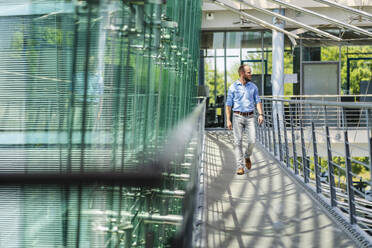 Businessman walking in corridor of modern office building - DIGF20408