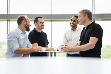 Group of businessman having informal meeting standing in office hall with cups of coffee - DIGF20425