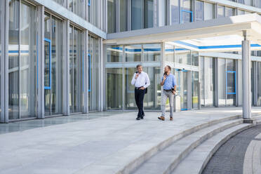 Two managers walking in modern building talking business - DIGF20447