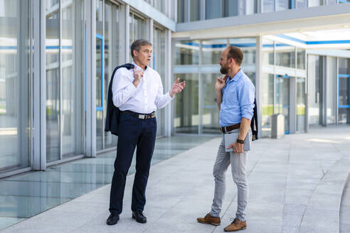 Zwei Führungskräfte besprechen geschäftliche Angelegenheiten in einer eleganten, modernen Büroumgebung - DIGF20452