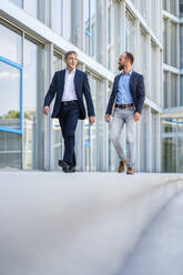 Two managers walking in modern building talking business - DIGF20458