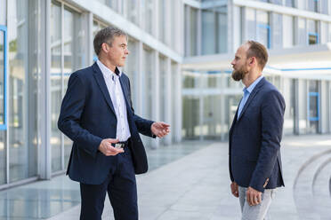 Competent businessman listening to colleague in office building - DIGF20459