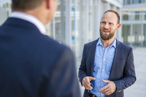 Competent businessman listening to colleague in office building - DIGF20464