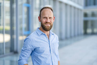 Casual businessman standing in front of office building - DIGF20508