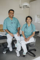 Portrait of smiling male and female healthcare professionals sitting in hospital - MASF37452